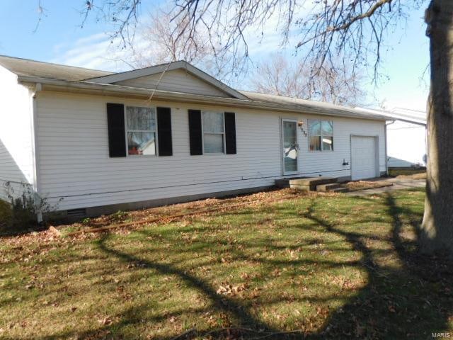 rear view of house featuring a lawn and a garage