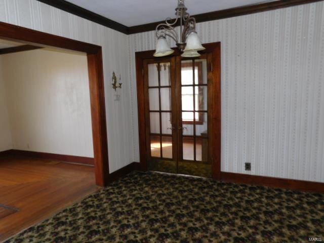 unfurnished dining area with ornamental molding, a chandelier, and french doors