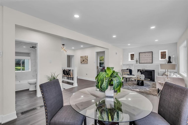 dining room featuring ceiling fan, dark wood-type flooring, and a premium fireplace