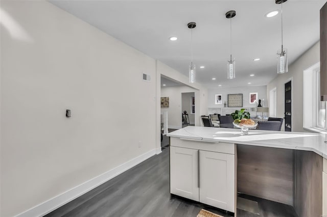 kitchen featuring light stone countertops, dark hardwood / wood-style flooring, white cabinets, and decorative light fixtures