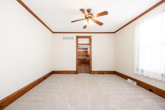 empty room with ceiling fan, light colored carpet, and ornamental molding