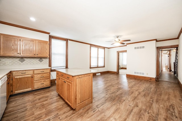 kitchen with ceiling fan, ornamental molding, tasteful backsplash, a center island, and light wood-type flooring