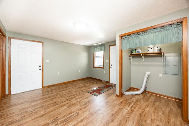 laundry room featuring electric panel and light hardwood / wood-style floors