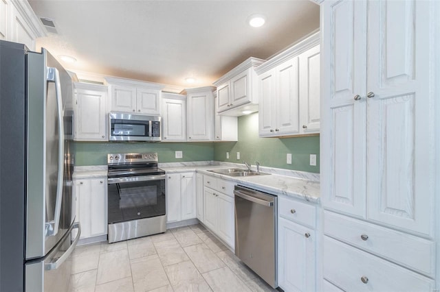 kitchen featuring light stone countertops, white cabinets, appliances with stainless steel finishes, and sink