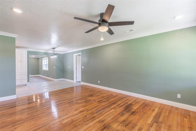 empty room featuring a textured ceiling, ornamental molding, light wood-type flooring, and ceiling fan