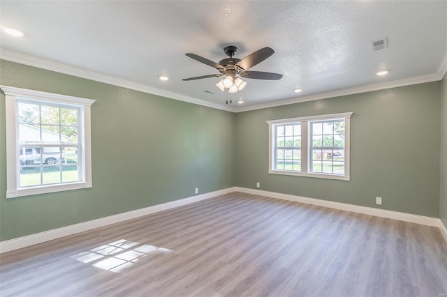 spare room with ceiling fan, light wood-type flooring, crown molding, and a wealth of natural light