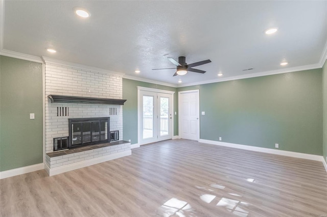 unfurnished living room featuring ceiling fan, light wood-type flooring, crown molding, and a brick fireplace