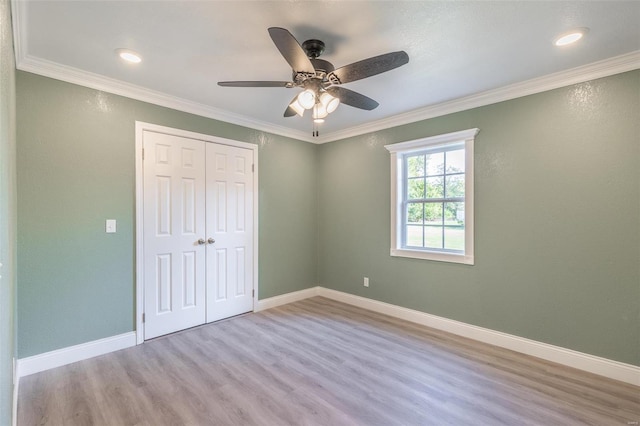 unfurnished bedroom with a closet, crown molding, light hardwood / wood-style flooring, and ceiling fan