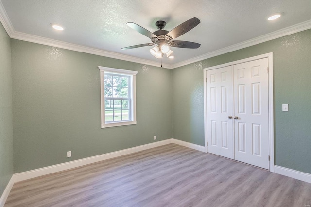 unfurnished bedroom with ornamental molding, ceiling fan, a closet, and light hardwood / wood-style floors