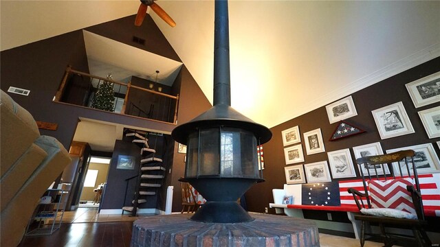 interior space with high vaulted ceiling, a wood stove, and hardwood / wood-style flooring