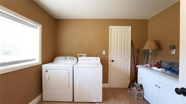 laundry area with separate washer and dryer, light tile patterned floors, and cabinets