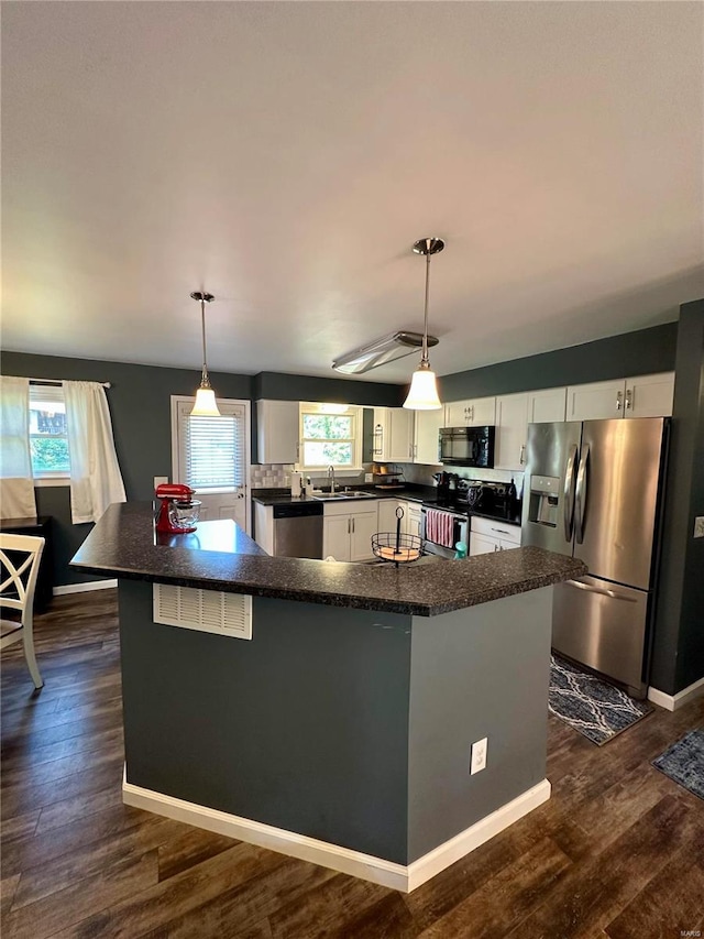 kitchen featuring pendant lighting, sink, dark wood-type flooring, white cabinetry, and appliances with stainless steel finishes