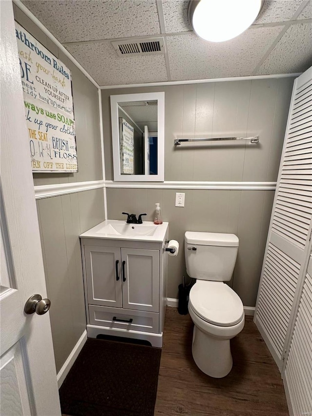 bathroom featuring vanity, hardwood / wood-style floors, toilet, and a paneled ceiling