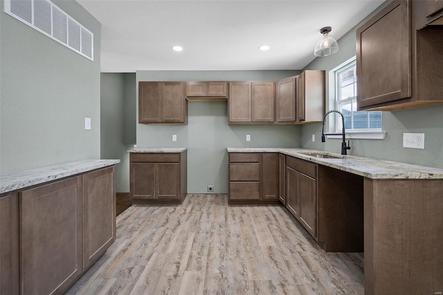 kitchen featuring light stone countertops, light hardwood / wood-style floors, and sink