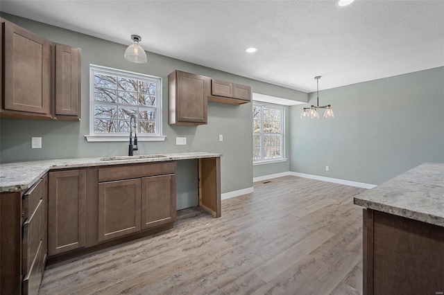 kitchen featuring a notable chandelier, pendant lighting, light hardwood / wood-style floors, sink, and a textured ceiling