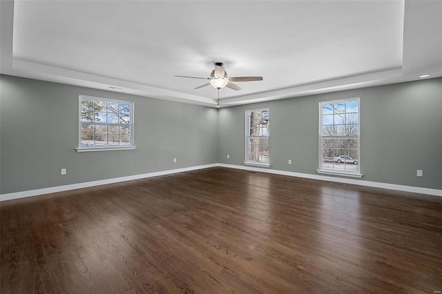 spare room featuring dark wood-type flooring, a tray ceiling, and ceiling fan