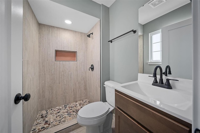 bathroom featuring toilet, vanity, and a tile shower