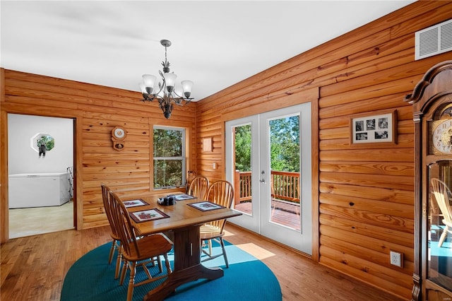 dining space featuring a notable chandelier, french doors, and light hardwood / wood-style flooring