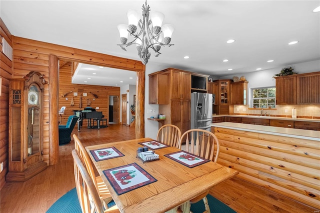 dining area with hardwood / wood-style floors, an inviting chandelier, and wooden walls