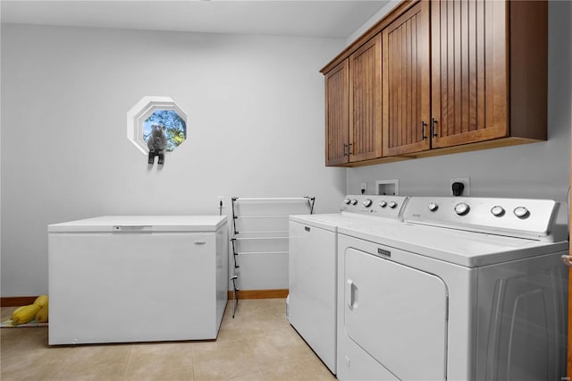 laundry room with light tile patterned flooring, washer and clothes dryer, and cabinets