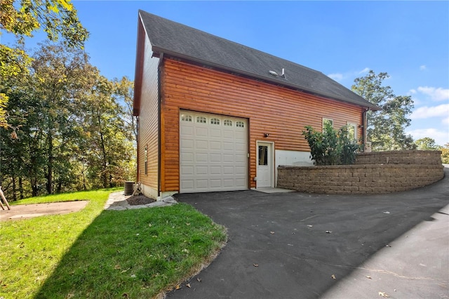 view of side of home with a yard, central AC, and a garage