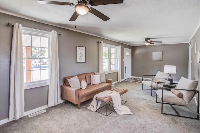 living room with light carpet, a textured ceiling, ceiling fan, and a healthy amount of sunlight