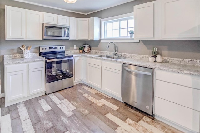 kitchen featuring light hardwood / wood-style flooring, appliances with stainless steel finishes, sink, and white cabinetry