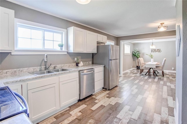 kitchen with white cabinets, light hardwood / wood-style floors, appliances with stainless steel finishes, and sink