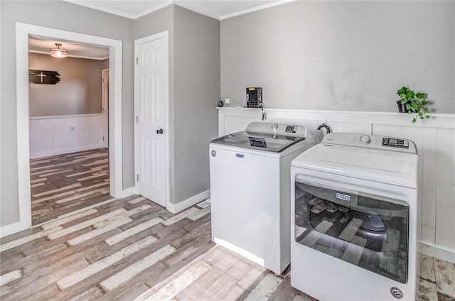 clothes washing area with light wood-type flooring, ornamental molding, and washing machine and dryer