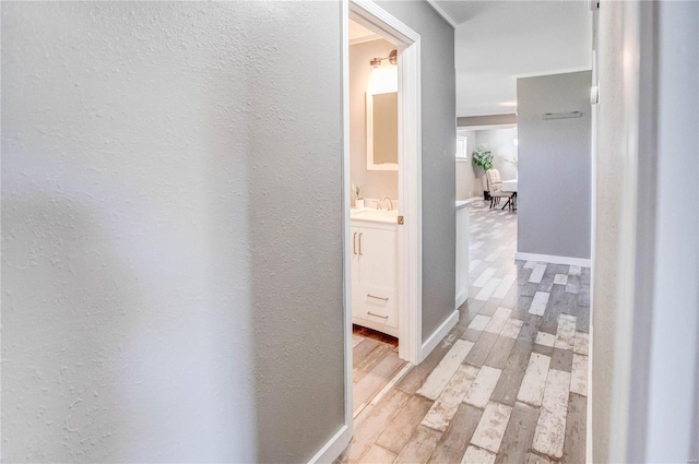 hallway with light wood-type flooring and sink