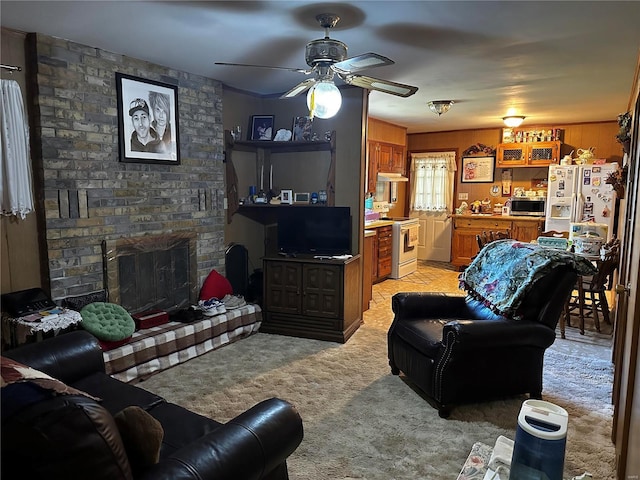living area with light carpet, a ceiling fan, and a brick fireplace