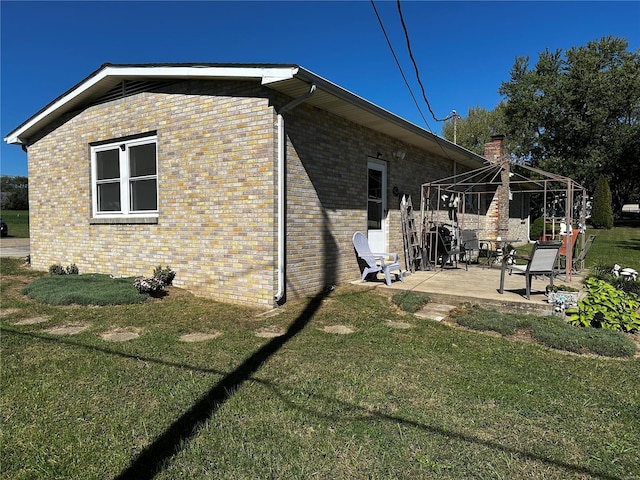 view of side of property with a yard, a gazebo, a patio area, and brick siding