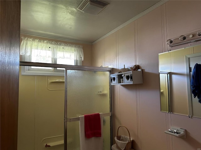 bathroom featuring crown molding, visible vents, a shower stall, and a decorative wall