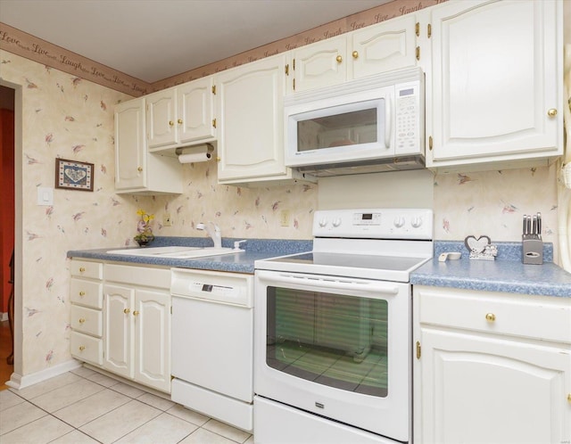 kitchen featuring light tile patterned floors, white cabinets, sink, and white appliances