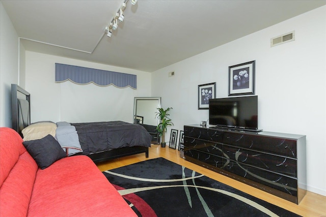 bedroom with hardwood / wood-style floors and rail lighting