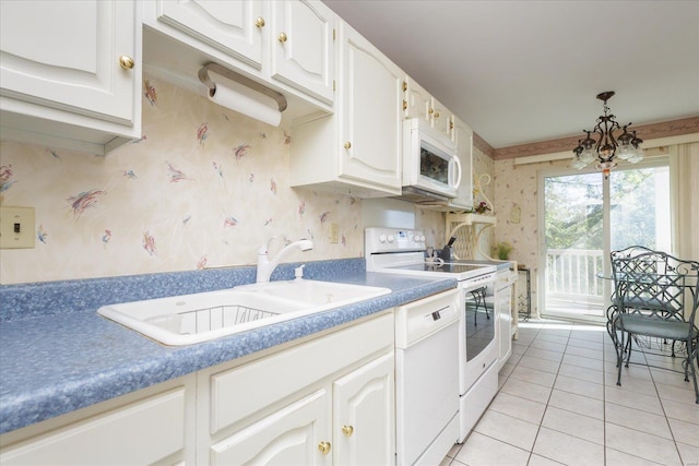 kitchen featuring white cabinets, light tile patterned flooring, sink, white appliances, and an inviting chandelier