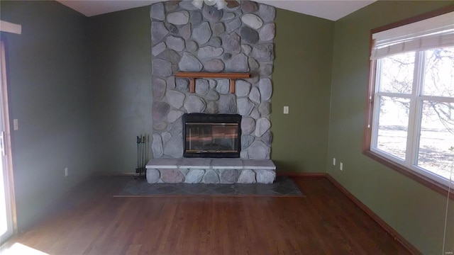 unfurnished living room with a wealth of natural light, a stone fireplace, and wood-type flooring