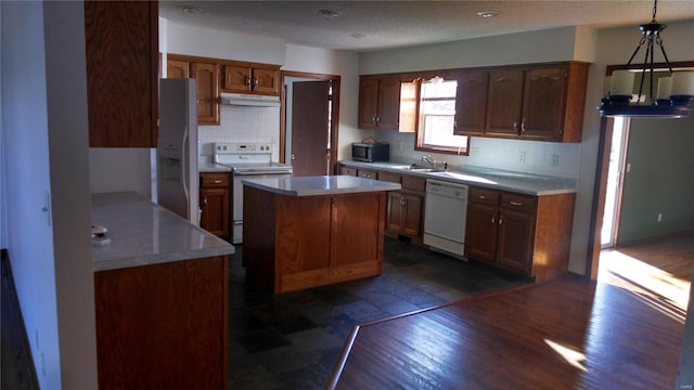 kitchen with pendant lighting, white appliances, tasteful backsplash, and a center island