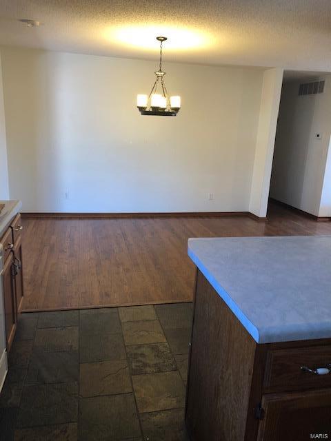 kitchen with hanging light fixtures, dark hardwood / wood-style floors, a chandelier, and a textured ceiling