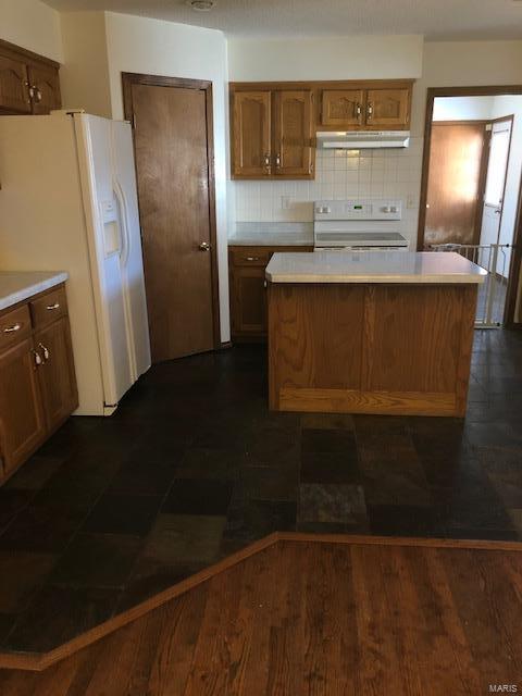 kitchen featuring a kitchen island, decorative backsplash, and white appliances