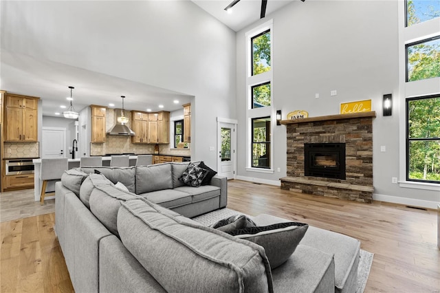 living room featuring a wealth of natural light, a towering ceiling, and light hardwood / wood-style flooring