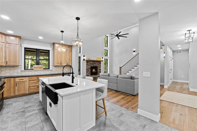 kitchen featuring a kitchen island with sink, tasteful backsplash, light hardwood / wood-style flooring, a kitchen breakfast bar, and hanging light fixtures