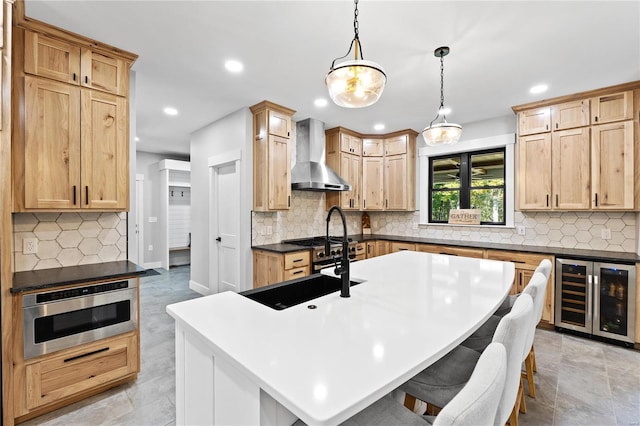 kitchen with a center island with sink, wall chimney exhaust hood, wine cooler, and a kitchen breakfast bar