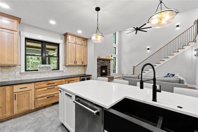 kitchen with decorative backsplash, dishwasher, decorative light fixtures, and a stone fireplace