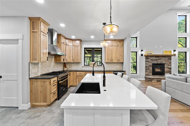 kitchen with high end stove, wall chimney exhaust hood, and a wealth of natural light