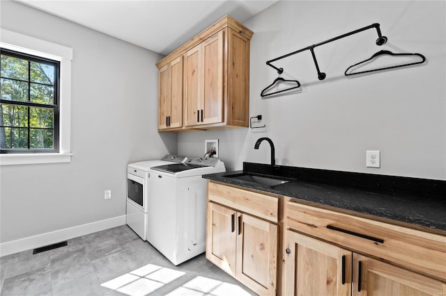 clothes washing area with separate washer and dryer, cabinets, and sink