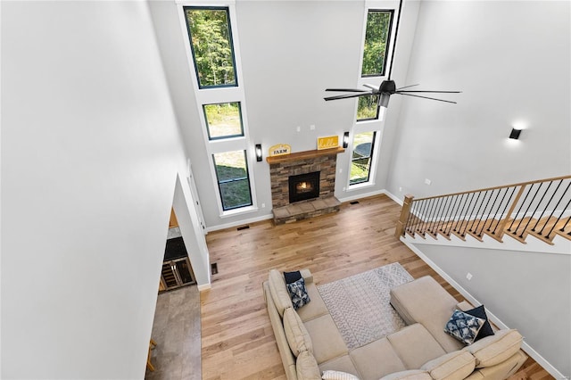 living room with a fireplace, a high ceiling, light wood-type flooring, and a healthy amount of sunlight