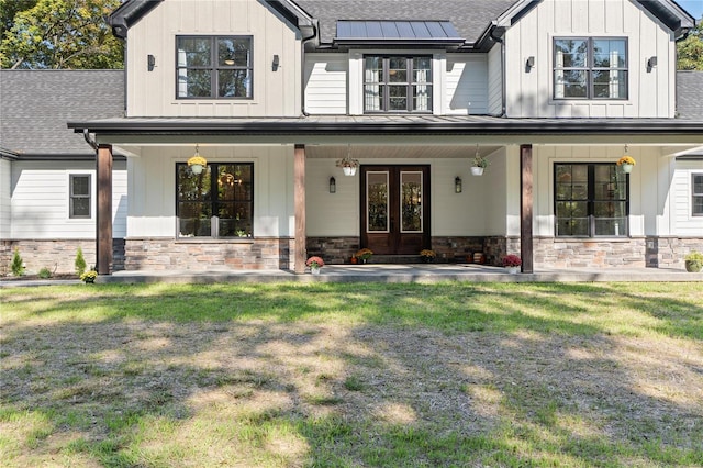 view of front facade featuring french doors, a front lawn, and covered porch