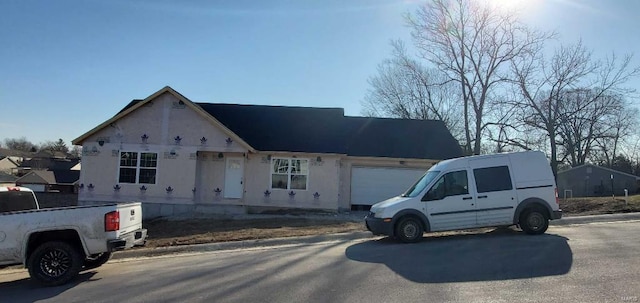 view of front of home with stucco siding, driveway, and an attached garage