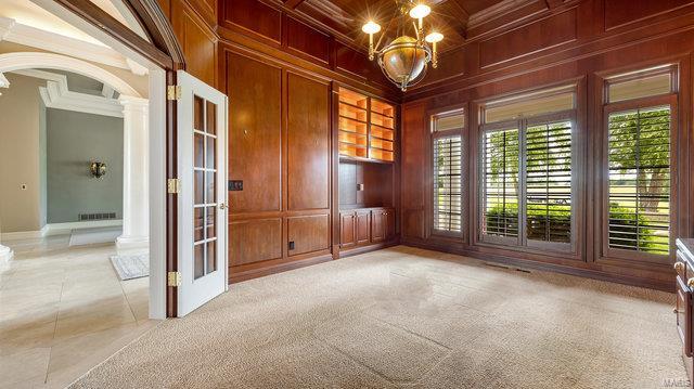 empty room with ornate columns, wooden walls, and ornamental molding